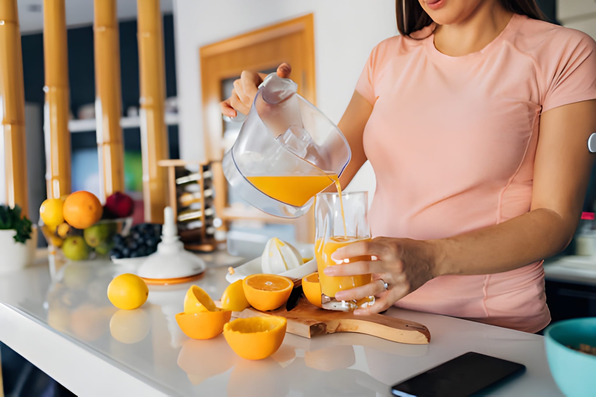 close up of a young pregnant woman pouring juice from a juicer into a drinking glass