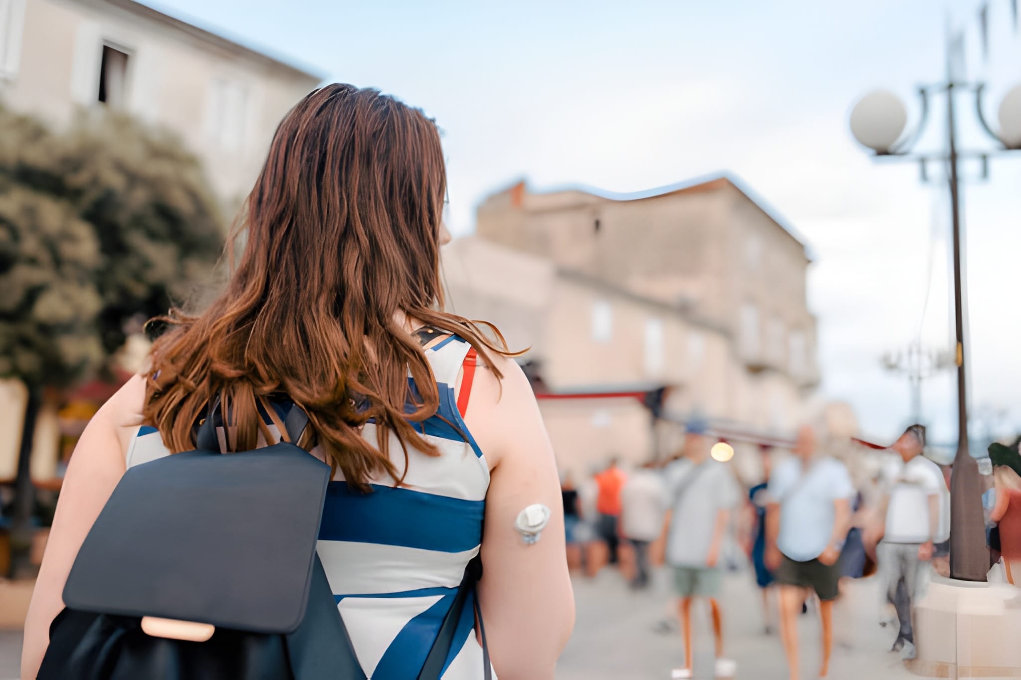 woman exploring the city wearing a continuous glucose monitor and a backpack