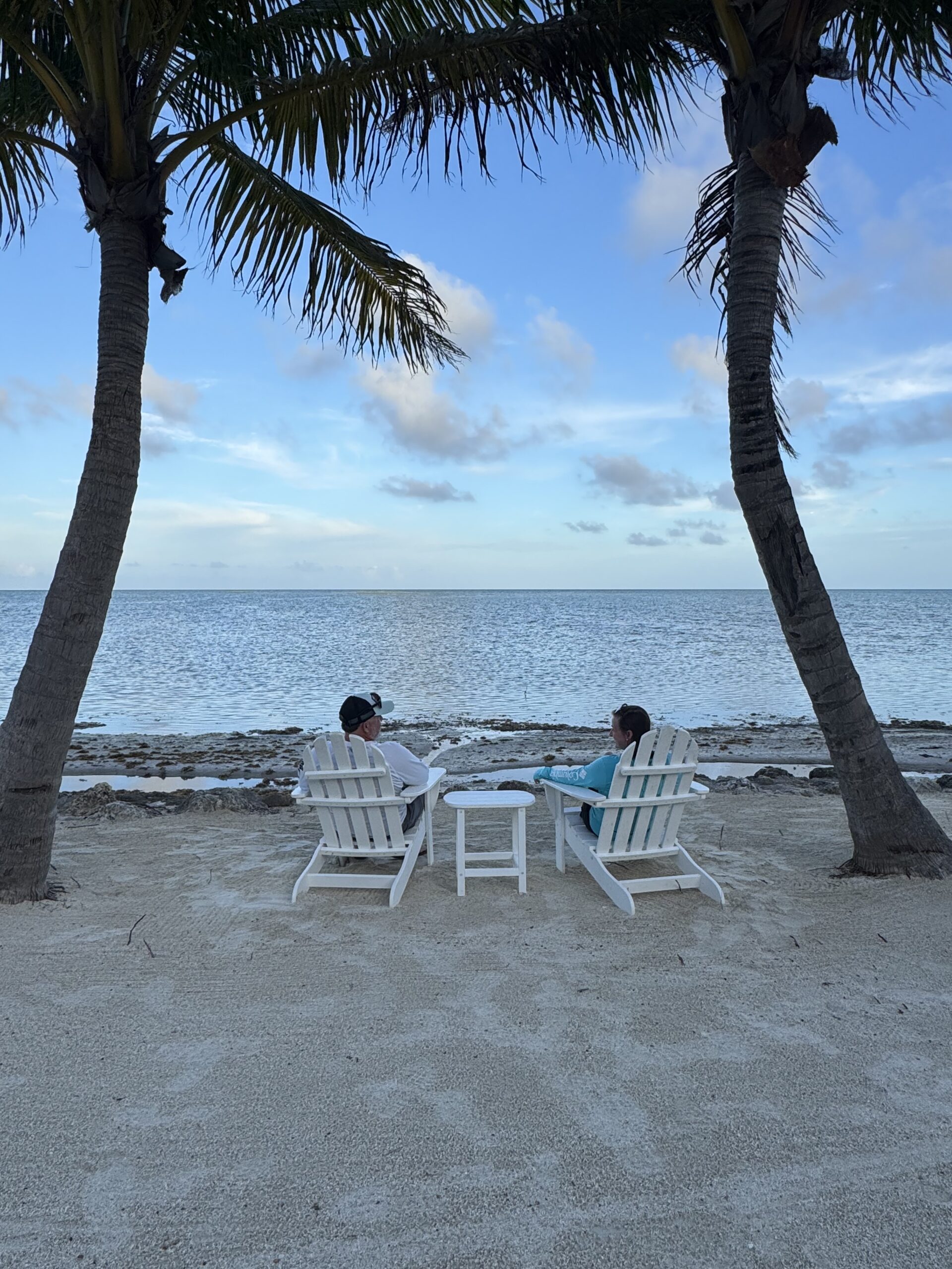 Couple relaxing near the water at a tropical resort, representing stress-free travel and preparation. 